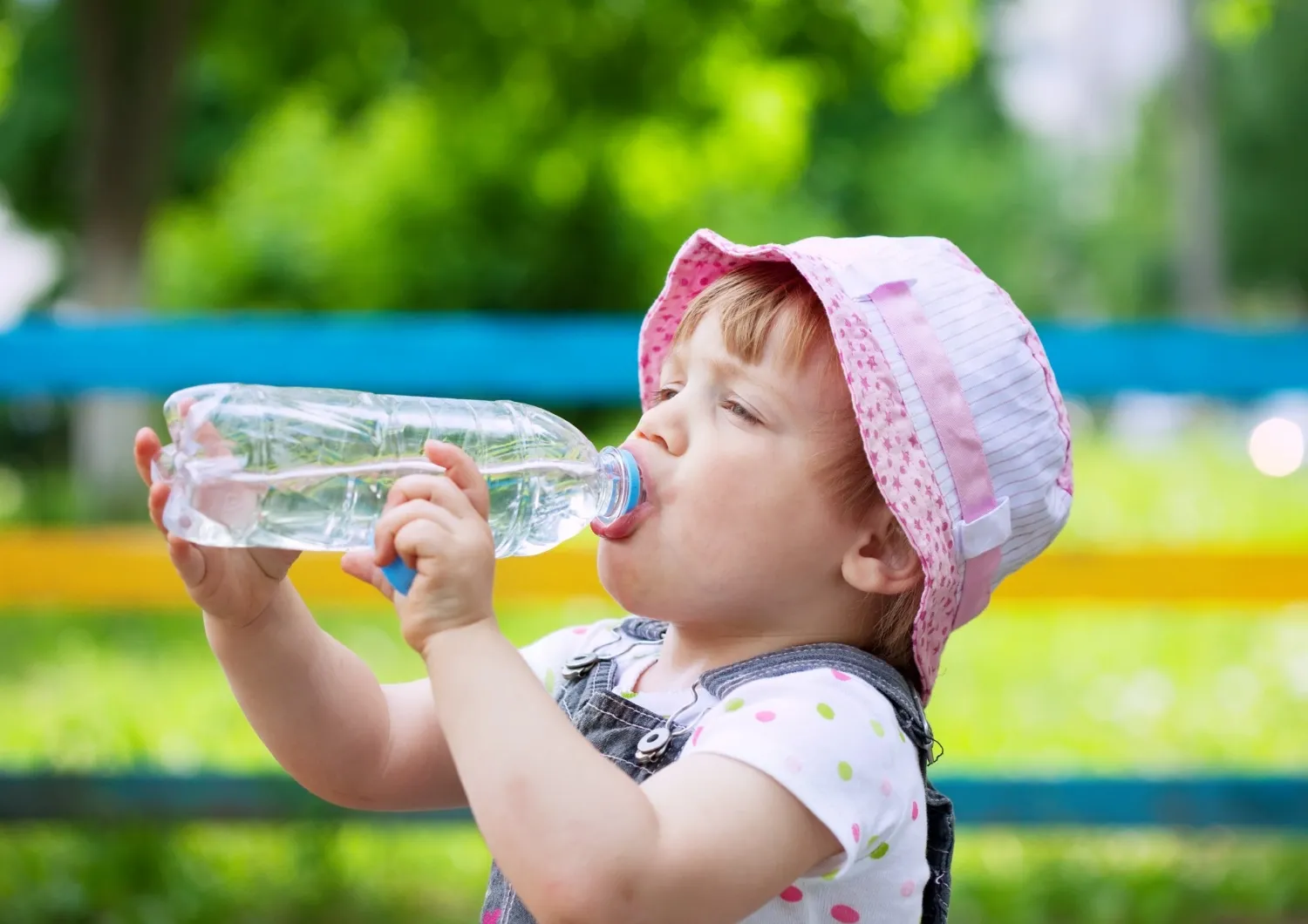 Rainwater marka su içen çocuk, yaz günü parkta serinliyor.